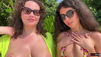 Wet girlfriends play on a public beach and pee on each other