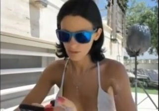 Sandy Yardish having a cigarette outside in swimsuit.