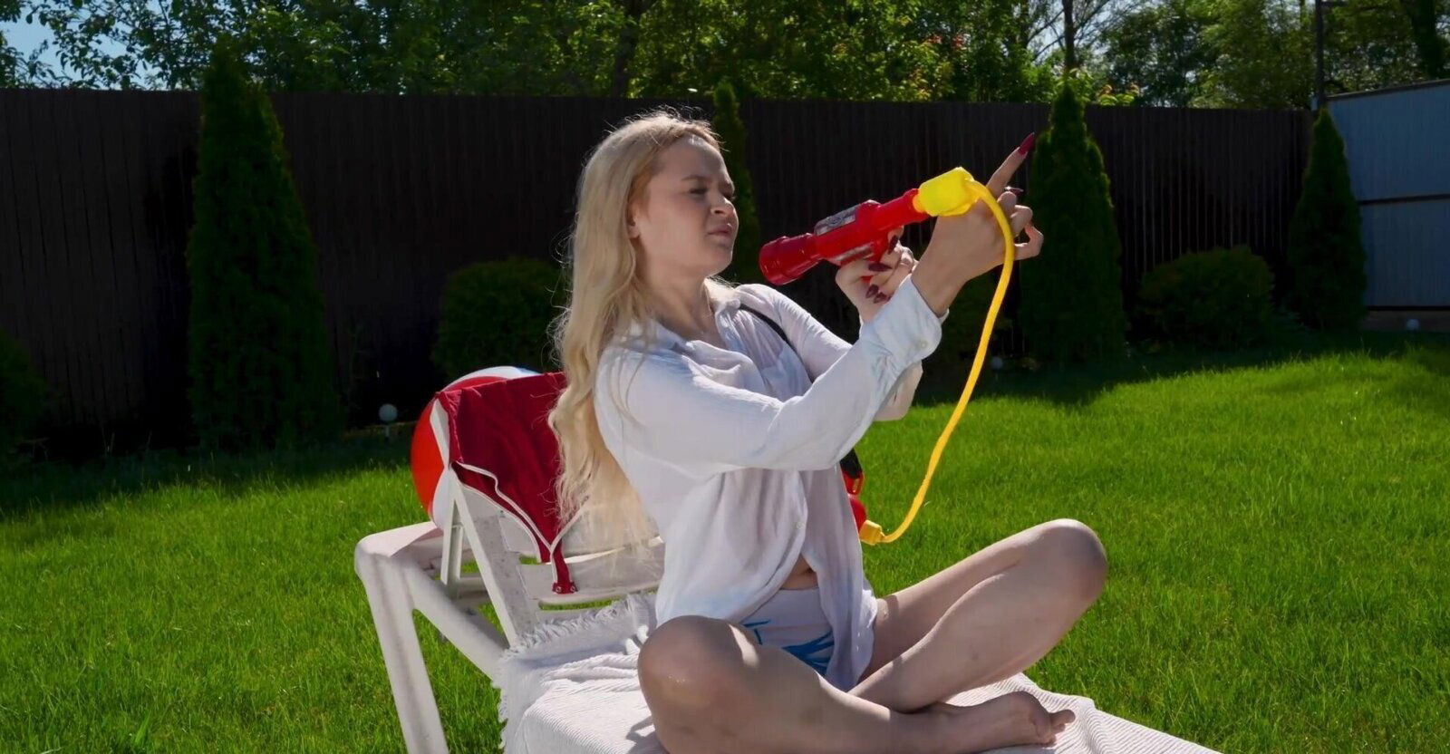 A blonde girl, Lina Shisuta, masturbates in the garden.