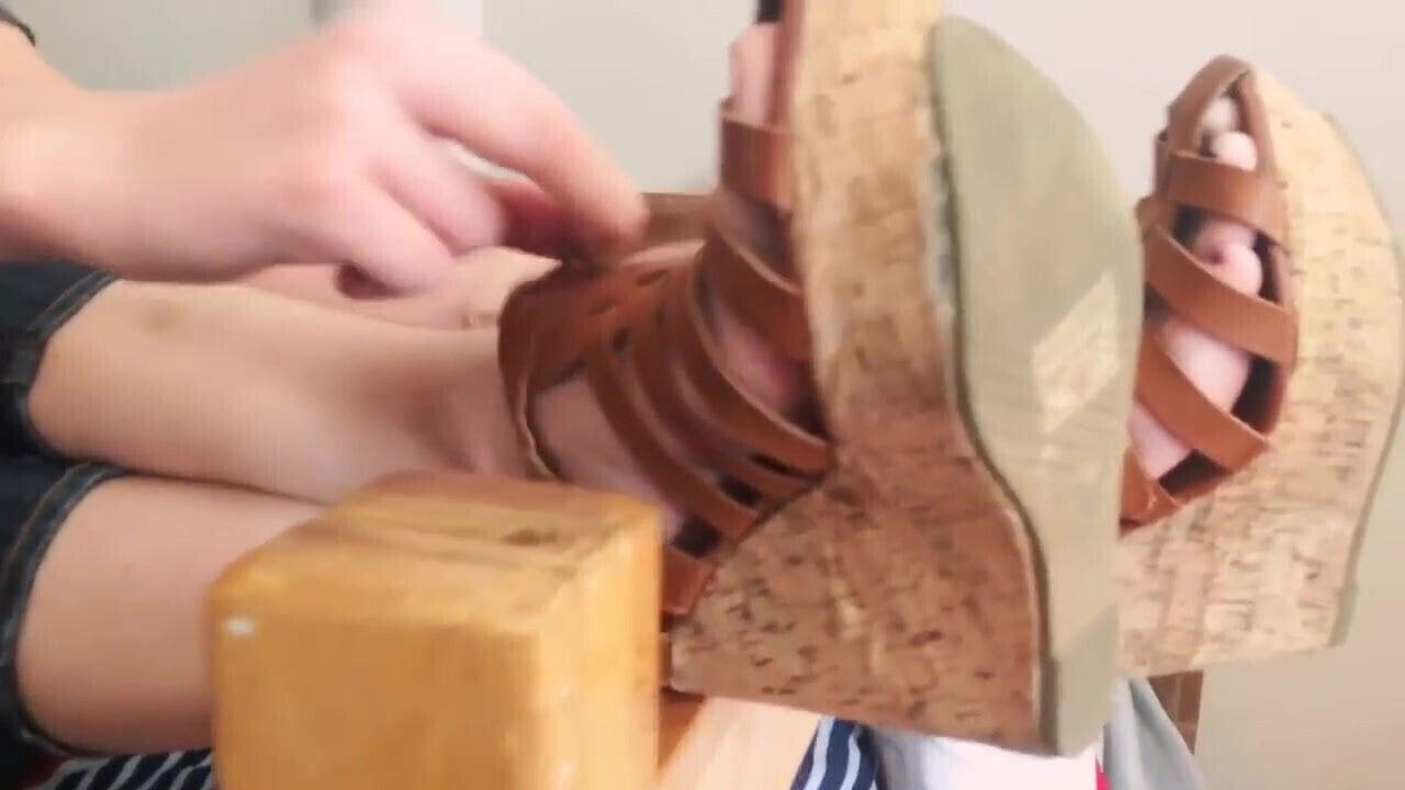 Pretty blonde removes wedge sandals and shows sweet soles.