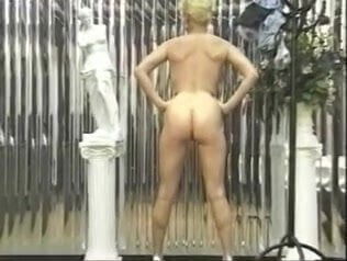 Busty blonde strips and poses nude in bedroom