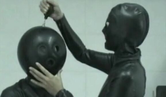 Two Girls In Black Latex Catsuits With Ballhood And Inflateable Mittens