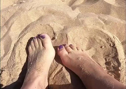 Provocative feet play sand, public.