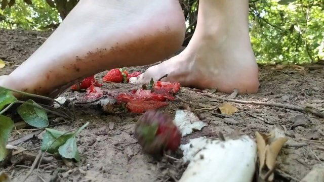 Barefooted fruit crush girl tramples banana strawberries