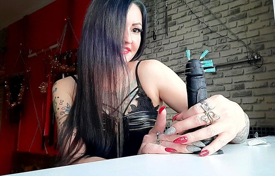 Dominatrix Nika pierces dildo with needles.