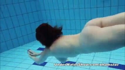 Redheaded cutie swimming nude pool
