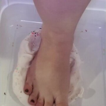 Feet squishing rainbow sprinkle cream slime
