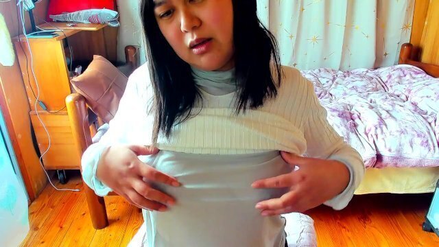 busty Japanese woman enjoys masturbating nipples through see-through top.