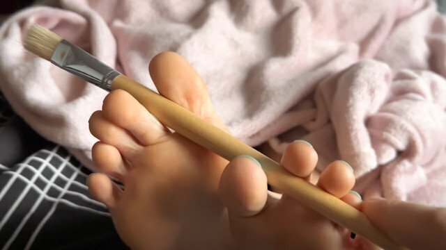 Friend tickles soles with painting brushes. Close feet worship